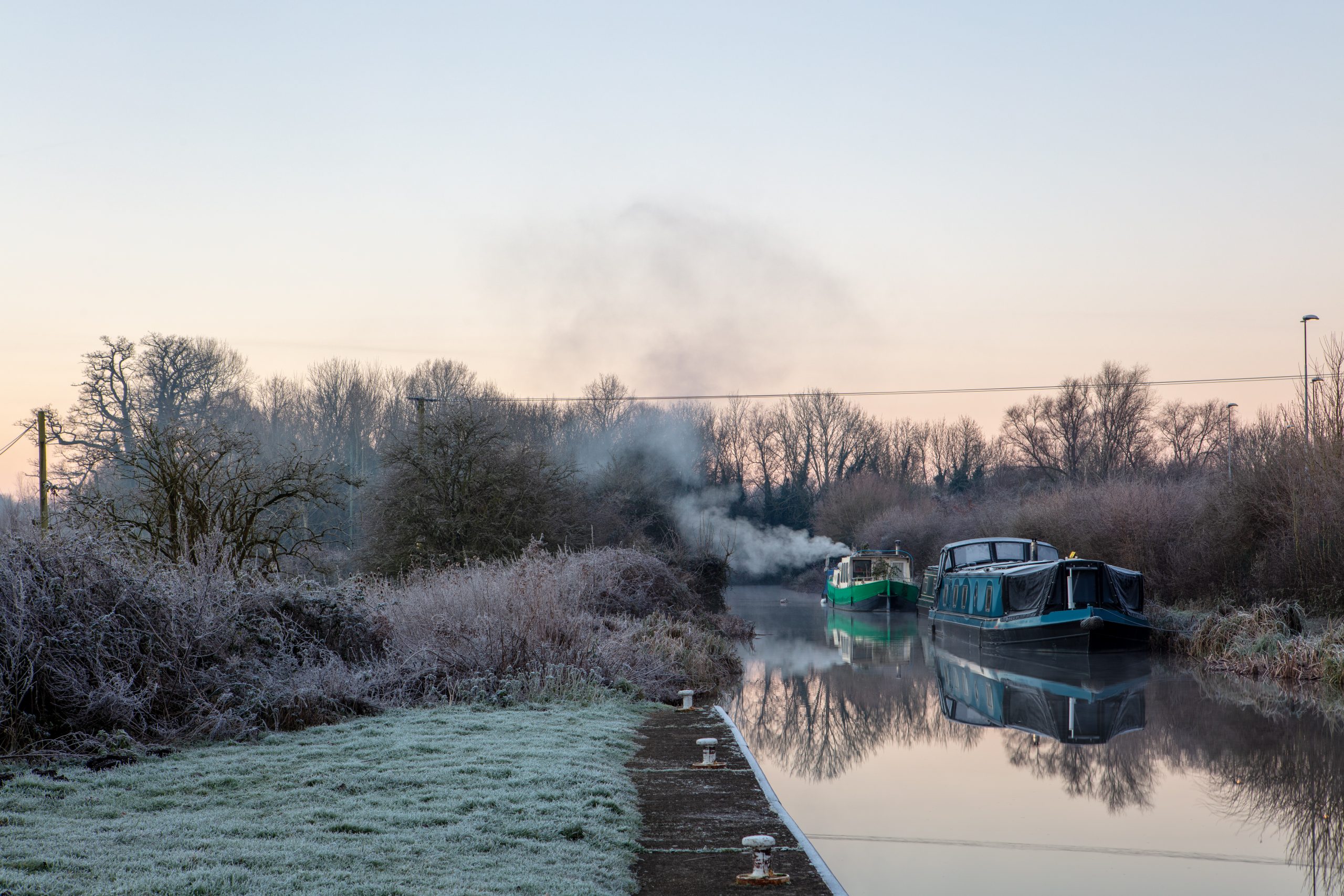 Image from blog 'winter photography tips' showing the Kennet and Avon Canal early morning. Narrow boats with stoves going keeping warm on the icy cold waters. 