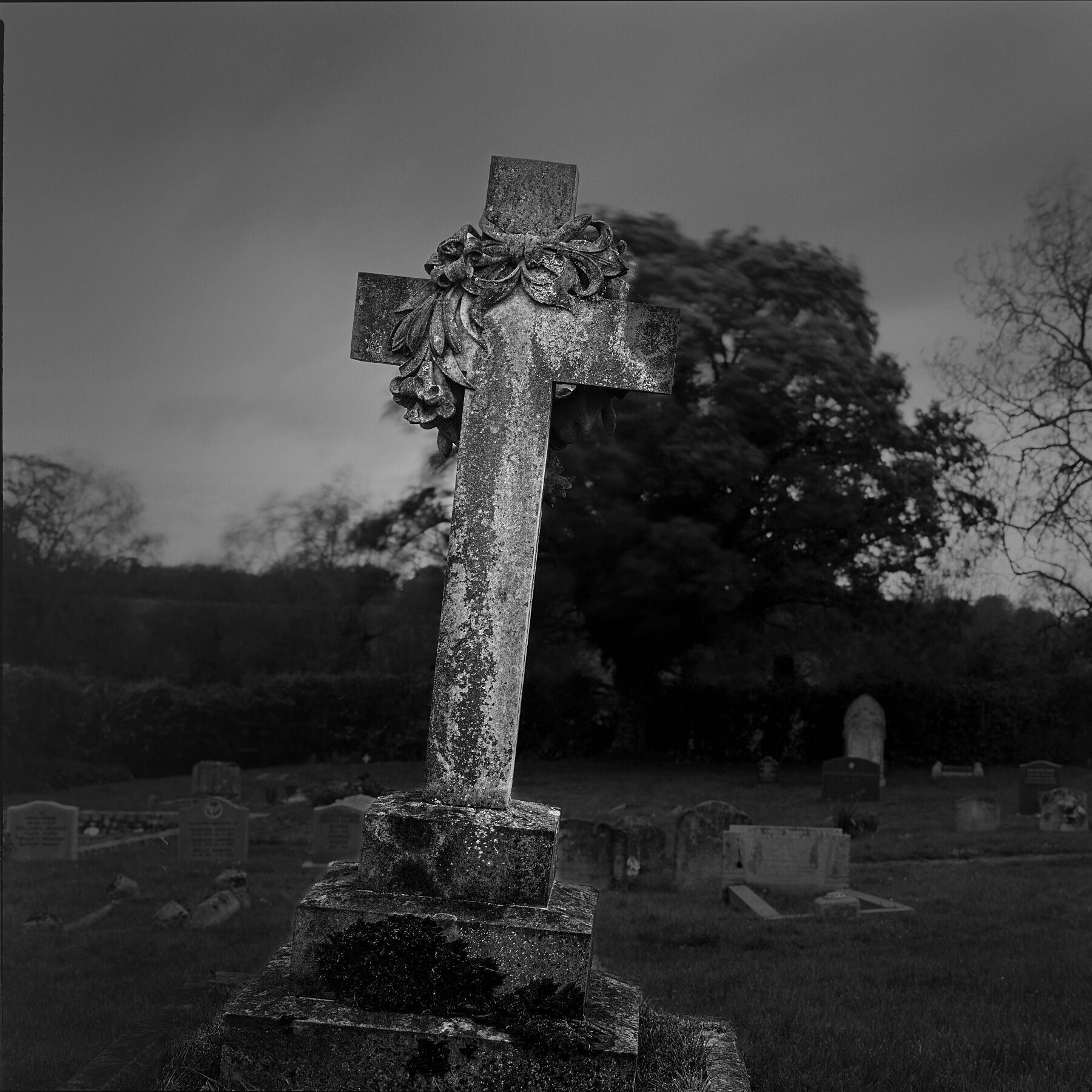 Black and white film photo of a churchyard cross. Taken at Silchester 12th Century Church, England. Explore more of my photography at https://fineartpics.co.uk