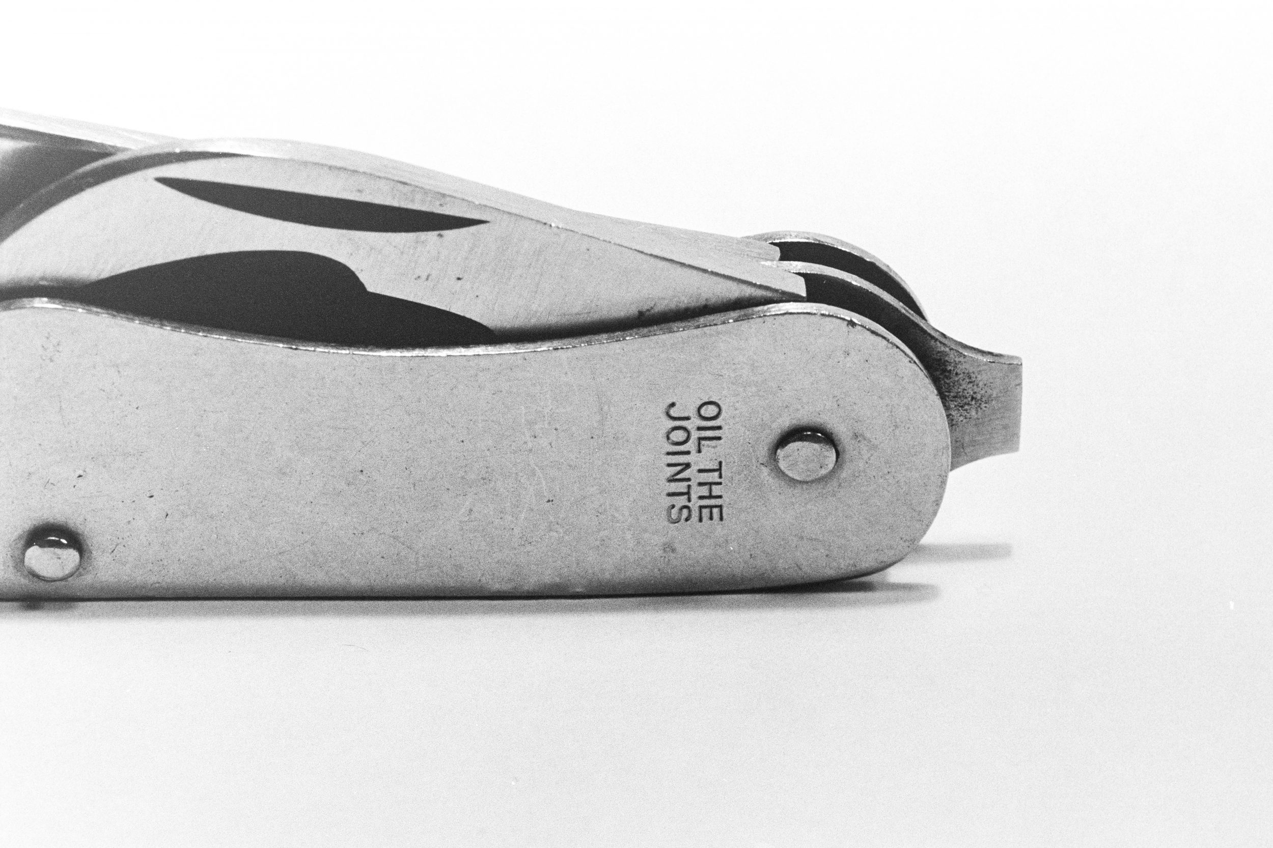 Minimalist Pocket Knife - The black and white abstract picture depicts a pocket knife with a focus on its texture and engraving, creating a sense of minimalism. The lines and shadows of the knife create a captivating visual experience, much like a delicate dance of contrasts and subtleties. The picture evokes a feeling of precision and elegance, with the monochromatic tones enhancing the simplicity and sophistication of the subject.