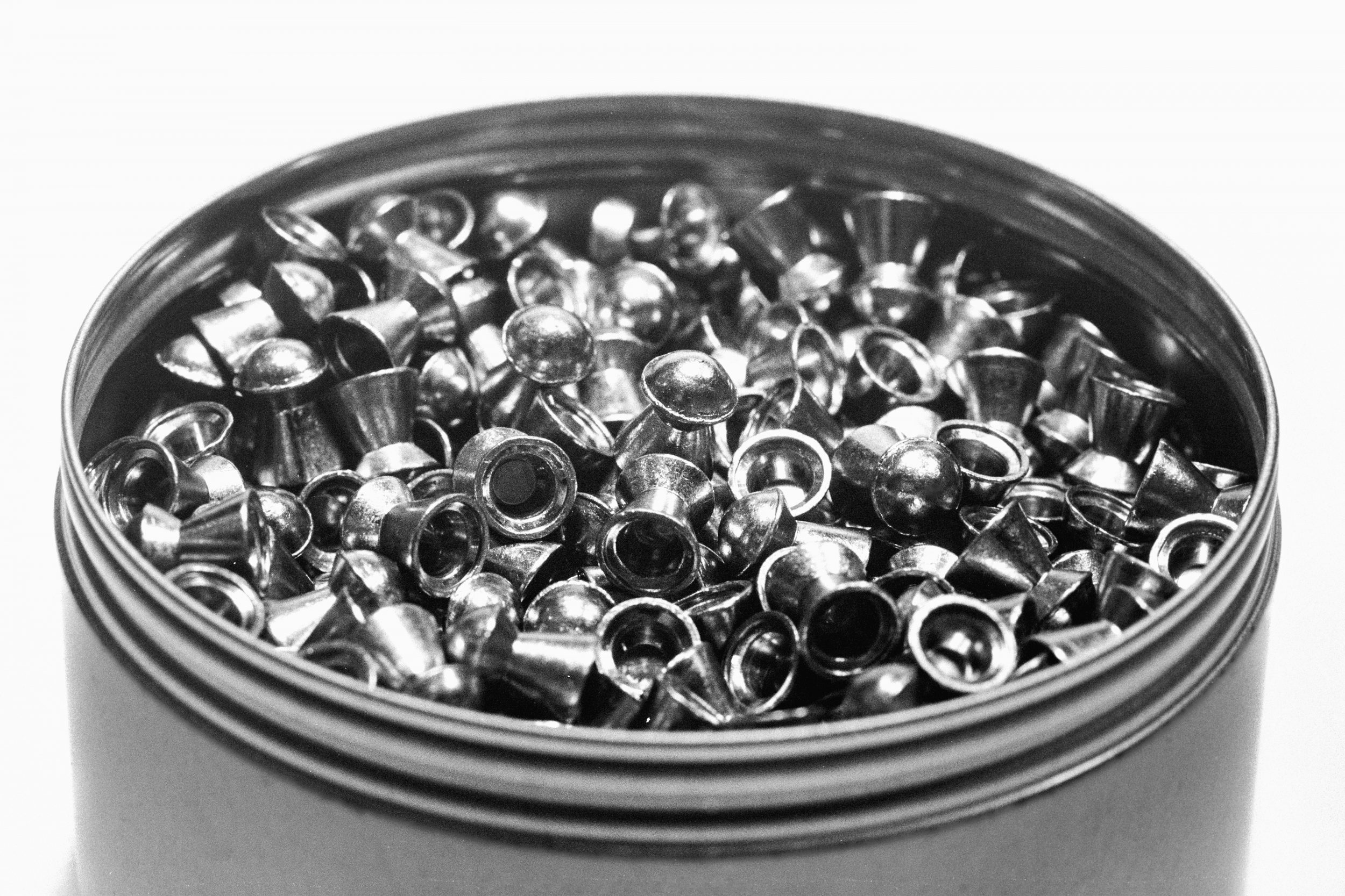 Tin of Air Pellets - In this captivating black and white abstract photograph, the tonality and texture of lead pellets create a mesmerising visual experience. The juxtaposition of black and white, and the intricate details of the air pellets and slugs, draw the viewer into a world of enigmatic wonder. The stark contrast and subtle gradations evoke a sense of mystery and depth, inviting contemplation.