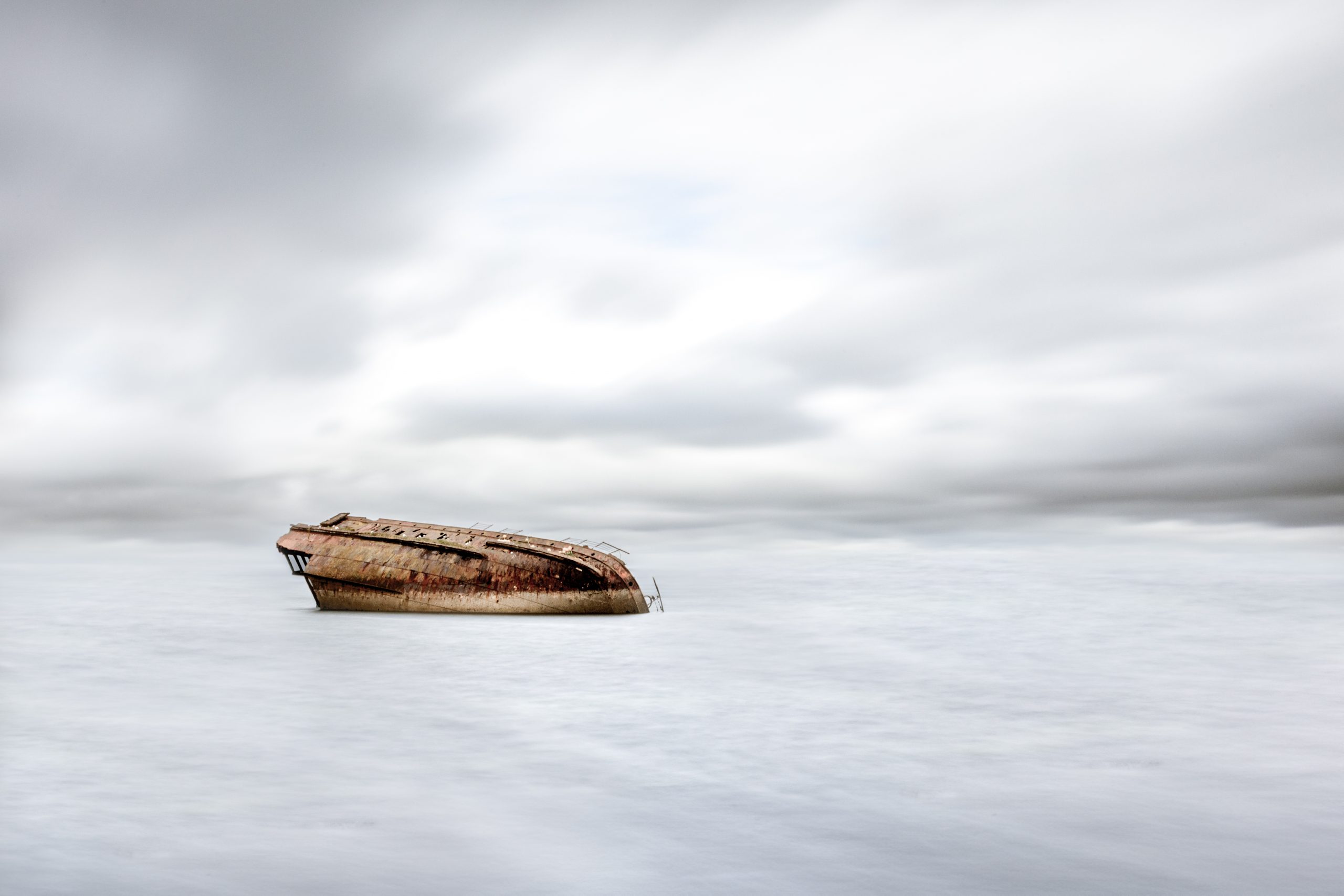A rust-covered shipwreck resting in the shallow, clear water of Scapa Flow, Orkney, Scotland.