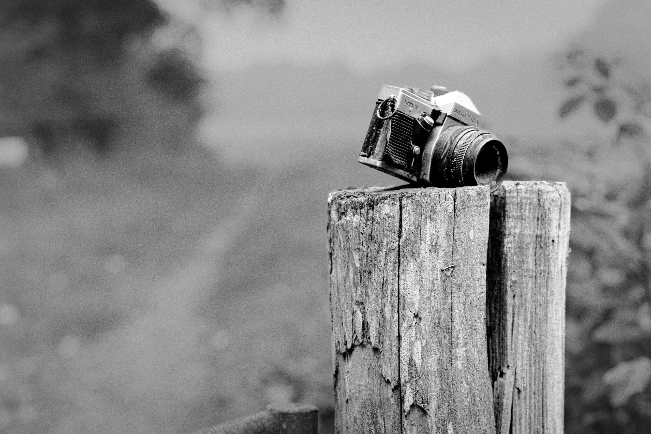 Weathered Practice MTL3 camera on a decaying fence post beside a footpath through the fields.